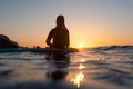 Surfer girl waiting for a wave in the water at sunset Royalty Free Stock Photo