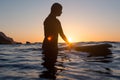 Surfer girl waiting for a wave in the water at sunset Royalty Free Stock Photo