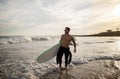 Surfer Guy. Young Man In Wetsuit Carrying Surfboard While Walking On Seashore Royalty Free Stock Photo