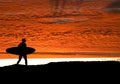 Surfer heading for ocean as the sun sets