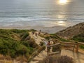 Surfer with his surf board going down the cliff to the beach during sunset Royalty Free Stock Photo