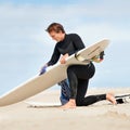 Surfer, man and getting ready with surfboard on beach with wetsuit, blue sky and cleaning with mock up space. Rear view Royalty Free Stock Photo