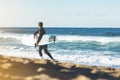Surfer man holding surfboard on background sea scape, sand beach coastline. Panorama horizon perspective view ocean, sunlight