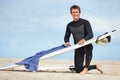 Surfer, man and portrait with surfboard by ocean with wetsuit, blue sky and cleaning with mock up space. Extreme sports Royalty Free Stock Photo