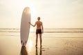 Surfer man stands with surf board on the beach summer sunset sea.romantic freelancer male tropical paradise rest and Royalty Free Stock Photo