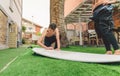 Surfer man with wetsuit waxing woman surfboard Royalty Free Stock Photo