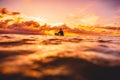 Surfer in ocean at sunset or sunrise. Winter surfing in ocean Royalty Free Stock Photo