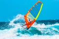 A surfer with orange and yellow sail riding the wave Royalty Free Stock Photo