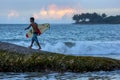 A surfer prepares to jump off Eight Star Rock to surf a beach break in the late afternoon at Arugan Bay in Sri Lanka.