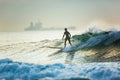 A surfer rides on the crest of a big wave with foam at sunset. Surfing man