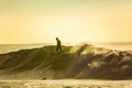 A surfer rides on the crest of a big wave with foam at sunset. Surfing man