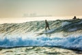 A surfer rides on the crest of a big wave with foam at sunset. Surfing man