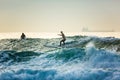 A surfer rides on the crest of a big wave with foam at sunset. Surfing man