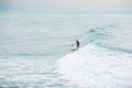 Surfer on stand up paddle board on blue wave. Winter surfing in ocean Royalty Free Stock Photo