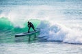 Surfer riding on stand up paddle board on breaking wave. Winter surfing in ocean Royalty Free Stock Photo