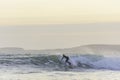 Surfer riding the wave in rough sea during sunset