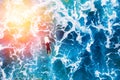Surfer rises on crest of wave in blue ocean. Aerial top view. Sunlight. Royalty Free Stock Photo