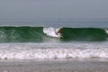 The surfer rolls on a surfboard on a wave in the Pacific Ocean.