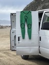 Surfer\'s green wetsuit hanging from the open door of the Van outside at the beach at Morro Rock