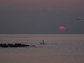 Surfer silhouette in front of sun at sunrise