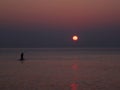 Surfer silhouette in front of sun at sunrise