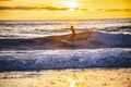 Surfer silhouette hitting a wave at sunset, golden hour, in the water of Newport Beach, California