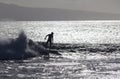 Surfer silhoutted against the silver waves