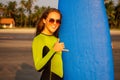 Surfer snow-white smile surfing girl in a stylish wetsuit showing gesture mahalo shaka hand sign signal saying hello on