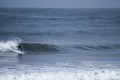 A surfer sportingly rides down a wave on a beach in Portugal Royalty Free Stock Photo