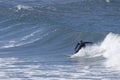 A surfer sportingly rides down a wave on a beach in Portugal Royalty Free Stock Photo