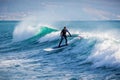 Surfer on stand up paddle board ride at wave. Winter surfing in ocean Royalty Free Stock Photo