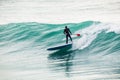 Surfer on stand up paddle board on blue wave. Winter surfing in ocean Royalty Free Stock Photo