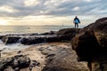 Surfer Standing on Rocks Watching the Waves at Sunset Time. Water Sport Concept. Copy Space Royalty Free Stock Photo