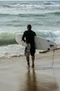 Surfer with surfboard on the beach watching at the ocean Royalty Free Stock Photo