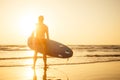 Surfer with surfboard looking at sunset at Goa India