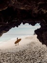 Surfer with surfboard posing on ocean beach. Woman with surf board and cave rocks in Bali Royalty Free Stock Photo