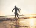 Surfer with surfboard runs in ocean waves, sunset time. Active l