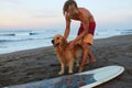 Surfer. Surfing Man Playing With Dog Near White Surfboard On Sandy Beach. Royalty Free Stock Photo