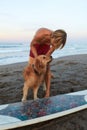 Surfer. Surfing Man Playing With Dog Near White Surfboard On Sandy Beach. Royalty Free Stock Photo