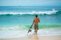 Surfer. Surfing Man With Surfboard Walking On Sandy tropical Beach. Healthy Lifestyle, water activities, Water Sport. Beautiful Royalty Free Stock Photo