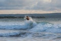 Surfer with a tanned body performs a trick on a short board - a jump over the waves. Royalty Free Stock Photo