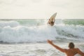 Surfer with a tanned body performs a trick on a short board - a jump over the waves.