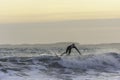 Surfer touching the wave while catching balance during evening surf in rough sea