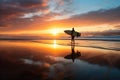 a surfer walking along the beach with a surfboard under his arm during sunrise Royalty Free Stock Photo