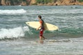 Surfer walking with his surfboard on a beach.