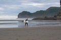 Surfer walking on Piha beach