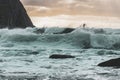 Surfer on a wave in the sea with many waves with the mountain on the left side of the image