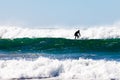 Surfer in wetsuit surfing breaking waves off beach