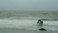 Surfer with windsurfing board approaching to the wavy water during bad stormy irish weather.