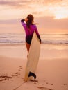 Surfer woman posing with surfboard on the beach at sunset Royalty Free Stock Photo